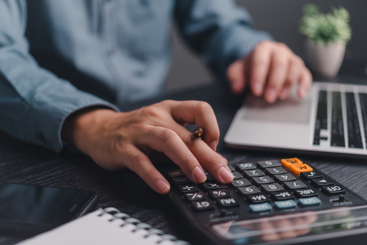 Close Up einer Hand auf einem Taschenrechner - Wir kalkulieren nach - FINACOACH Firmenkunden - Finanzpartner für B2B